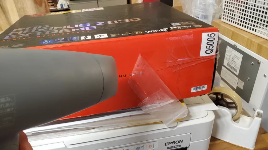 高級マザーボードの元箱がOPPテープでぐるぐる巻きになっていたので、ドライヤーで温めながら剥がす画像