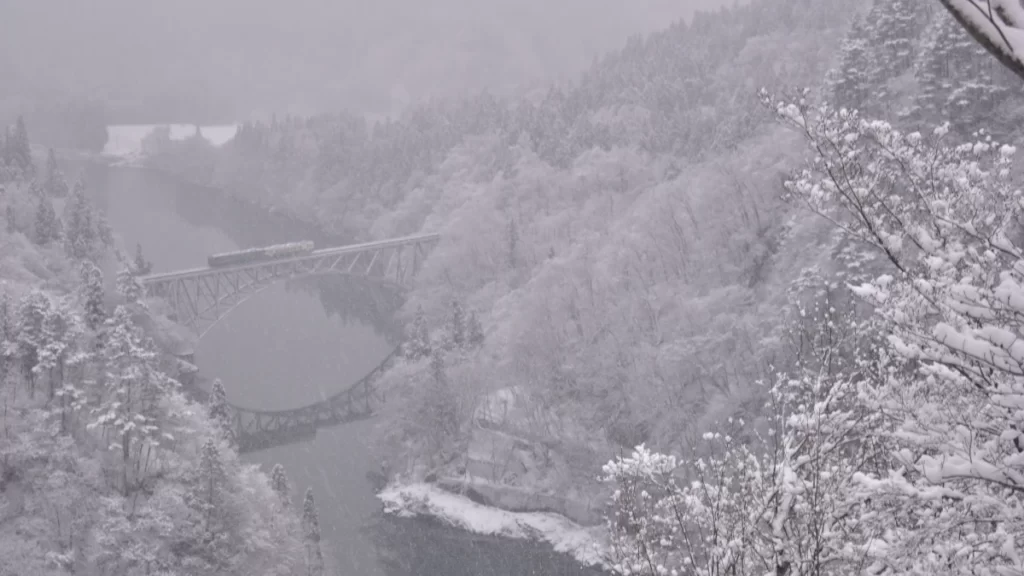 雪景色に包まれた山間部の鉄橋と冬の只見線の写真